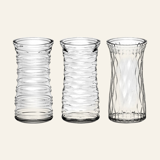Three clear glass vases with textured design on a white background