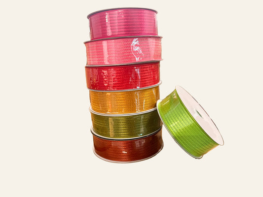 Stack of colorful spools of ribbon on white background